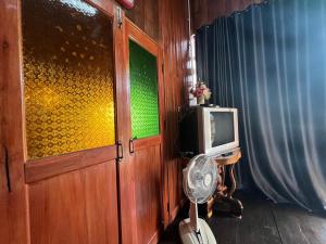 Zimmer mit einer Tür, einem TV und einem Ventilator in der Unterkunft กิ่วลม - ชมลคอร Kiwlom - Chomlakorn, Lampang, TH in Lampang