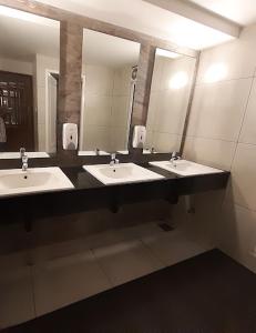 a bathroom with three sinks and two mirrors at Hotel Omkara in Kozhikode