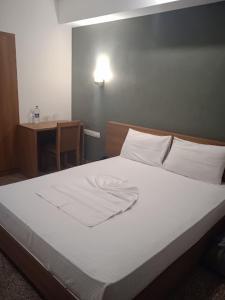 a bed with white sheets and pillows in a room at Hotel Omkara in Kozhikode