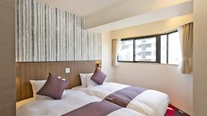2 Betten in einem Hotelzimmer mit Fenster in der Unterkunft Stay SAKURA Tokyo Asakusa Edo no Mai in Tokio