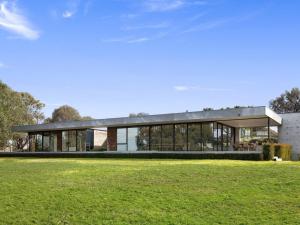 a house with a glass facade on a grass field at Cypress Hill in Apollo Bay