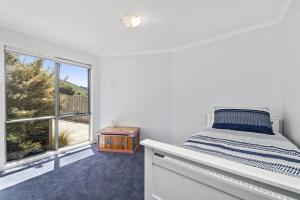 a white bedroom with a bed and a window at Poseidon in Apollo Bay