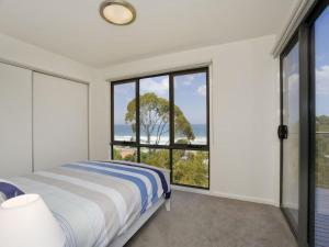 a bedroom with a bed and large windows at Earth Sea Sky in Wye River