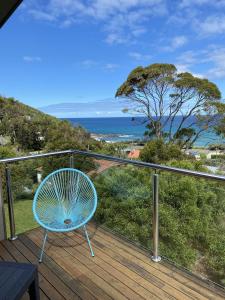 a blue chair sitting on a deck with a view of the ocean at Earth Sea Sky in Wye River