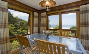 a dining room with a glass table and chairs and large windows at 2 Degrees of Separation in Wye River
