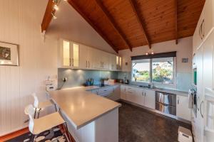 uma cozinha com armários brancos e uma grande janela em The Albatross em Port Campbell