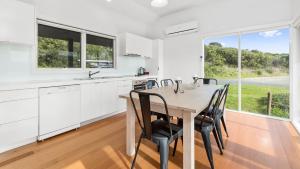 a white kitchen with a wooden table and chairs at Rivernook in Johanna