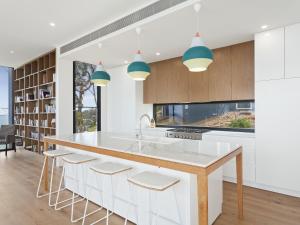 a kitchen with white cabinets and a large island with stools at Iluka Blue in Wye River