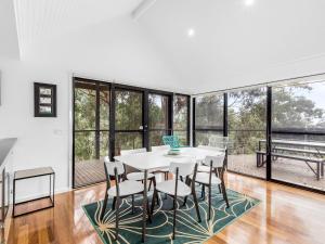 a dining room with a table and chairs and windows at Gulah in Wye River