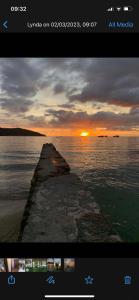 a picture of a pier in the water with the sunset at Orchid Sunset Guest House in Baie Lazare Mahé