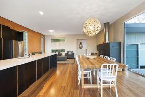 cocina y comedor con mesa de madera y sillas en Coastal Break, en Wye River