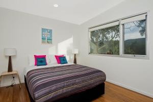 a white bedroom with a bed and two windows at Coastal Break in Wye River
