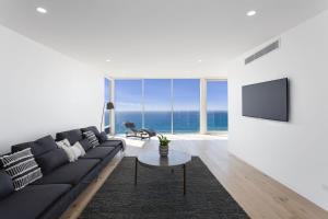 a living room with a black couch and a tv at Southpoint -Brand new home, oceanfront views in Wye River