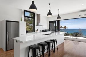 a kitchen with a large white island with black bar stools at The Cube in Wye River