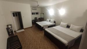 a hotel room with two beds and a table at Shangrela Beach Resort by ARK in Ambalangoda