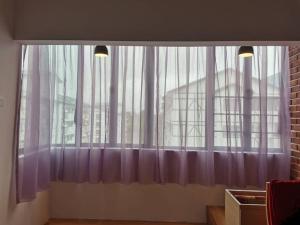 una gran ventana con cortinas moradas en una habitación en Cameron Homestay Adik Aisyah Purple Romance for Islam, en Tanah Rata