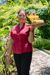 a woman holding a tray of food on a plate at Alamanda Lovina Resort in Lovina