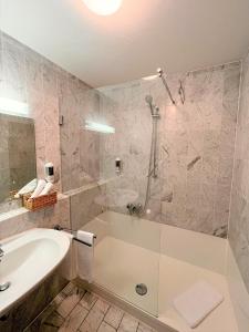 W łazience znajduje się prysznic, wanna i umywalka. w obiekcie Appartment-Hotel-Hölzl w mieście Grünwald