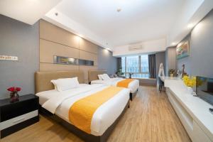 a hotel room with two beds and a television at Orange Tree International Hotel Zhujiang New Town US Consulate General Guangzhou Branch - Free Shuttle Bus to Canton Fair Complex During Canton Fair Period in Guangzhou