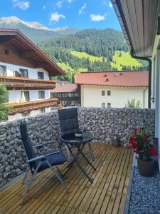 eine Terrasse mit einem Tisch und Stühlen auf einer Holzterrasse in der Unterkunft Apart Bubendorfer in Lermoos