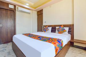 1 dormitorio con 1 cama blanca grande con almohadas coloridas en FabHotel The Sunrise, en Udaipur