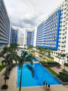 a large pool with palm trees in front of buildings at Bliss by John at Sea Residences in Manila