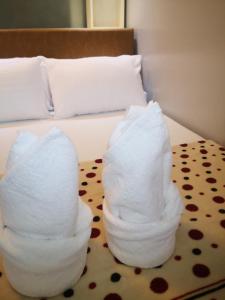 two stacks of towels sitting on top of a bed at Bliss by John at Sea Residences in Manila