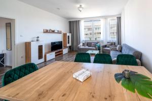 uma sala de estar com uma mesa de madeira e cadeiras verdes em Im Herzen Hannovers 3min City 95m² 3 Zimmer Balkon Aufzug em Hanôver