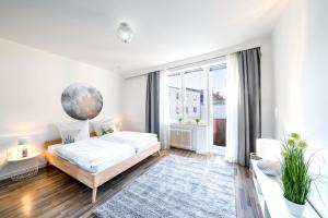 Dormitorio blanco con cama y ventana grande en Im Herzen Hannovers 3min City 95m² 3 Zimmer Balkon Aufzug, en Hannover