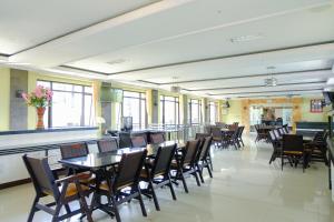 a dining room with tables and chairs and windows at Capital O 887 Green Hill Hotel And Convention Center in Jember