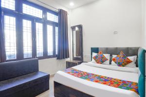 a bedroom with a bed and a couch and windows at FabHotel Royal Vilas in Gwalior