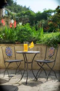 a table and two chairs with glasses of orange juice at Acorns with own hot tub, romantic escape, close to Lyme Regis in Uplyme