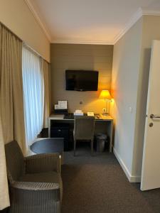 a hotel room with a desk and a tv at Hotel Atlas in Zeebrugge