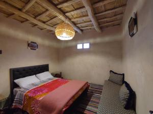 sypialnia z łóżkiem, żyrandolem i krzesłem w obiekcie Maroc des Merveilles - Chez L'habitant w mieście Kalaat M'Gouna