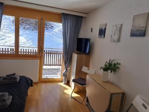 uma sala de estar com uma cama, uma mesa e uma janela em Haus Vitalis em Zermatt