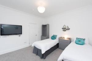1 dormitorio con 2 camas y TV de pantalla plana en Five-bedroom house at Margate, near beach and amenities en Margate