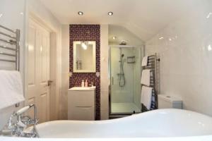 y baño con bañera, ducha y lavamanos. en Acorns with own hot tub, romantic escape, close to Lyme Regis en Uplyme