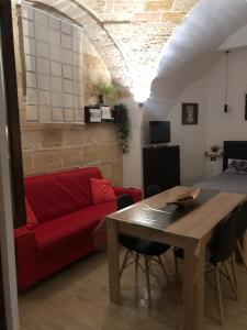 Casa Sipontina في بارليتا: غرفة معيشة مع أريكة حمراء وطاولة