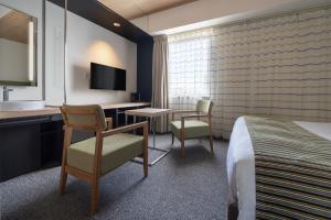 a hotel room with a bed and a desk and chair at Hotel Vista Hiroshima in Hiroshima