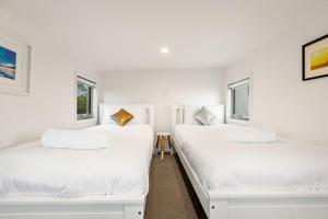 2 Betten in einem Zimmer mit weißen Wänden und Fenstern in der Unterkunft Daybreak Loft in Gold Coast
