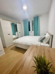 1 dormitorio con 1 cama con cortinas azules y mesa en MURIC Apartman 8, en Liubliana