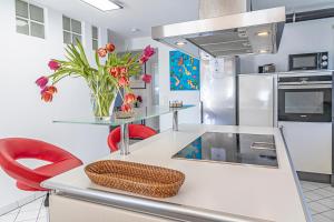 a kitchen with a counter with red chairs and flowers at Dream Flat near the fair - Apartment in Augsburg bei der Messe in Augsburg
