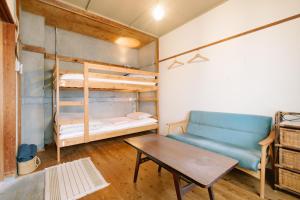 Guesthouse RICO في واكاياما: غرفة معيشة مع أريكة وسرير بطابقين