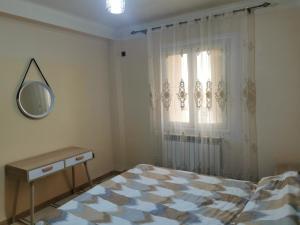 um quarto com uma cama, um espelho e uma janela em Appartement F4 de Luxe em Constantina