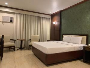 1 dormitorio con 1 cama, mesa y sillas en De Luxe Hotel, en Cagayan de Oro