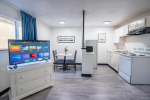 a kitchen with a large tv and a table with chairs at Kennewick Inn & Suites Tri Cities in Kennewick