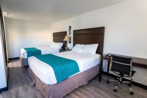 a hotel room with two beds and a desk and a chair at Kennewick Inn & Suites Tri Cities in Kennewick