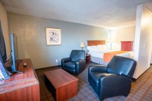 a hotel room with a bed and two chairs and a television at Kennewick Inn & Suites Tri Cities in Kennewick