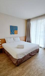 a bedroom with a large white bed in front of a window at Apo Hotel in Krabi