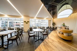 a restaurant with tables and chairs and windows at Hotel Vista Hiroshima in Hiroshima